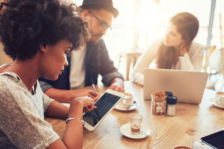 Young group of friends at a coffee shop using their devices