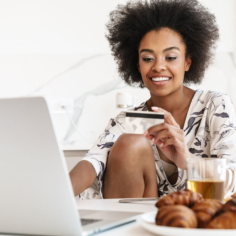 Excited young woman using a credit card for online shopping.