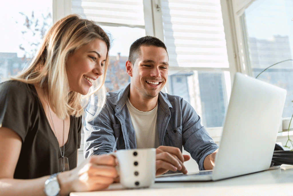 Smiling young couple looking at laptop personal finances