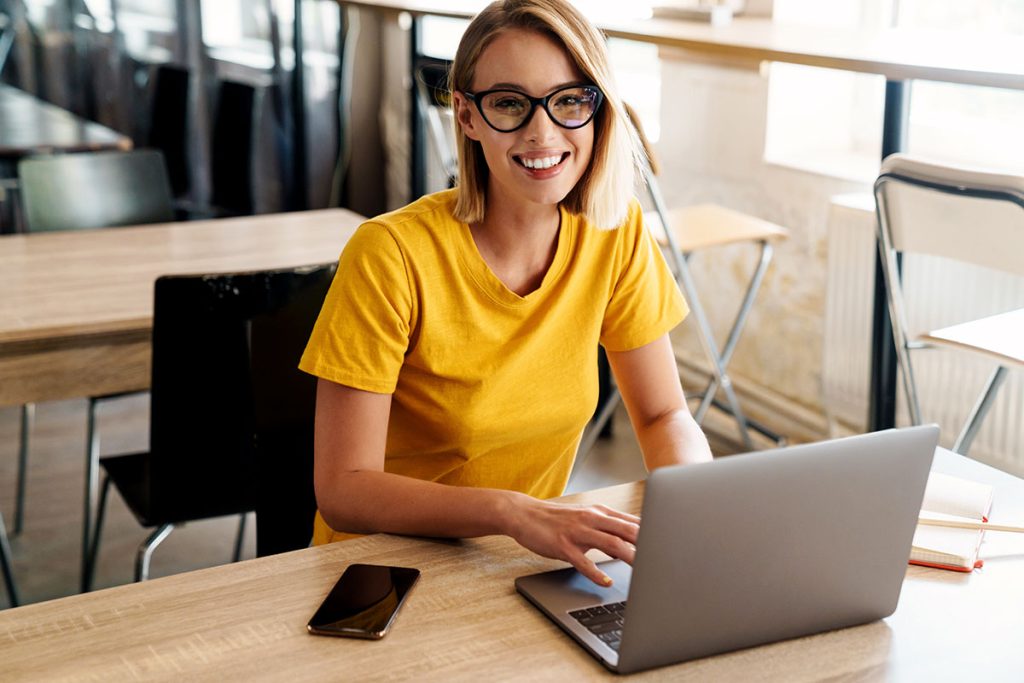 woman using laptop and smiling while sitting