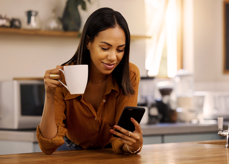 woman looking at phone holding coffee
