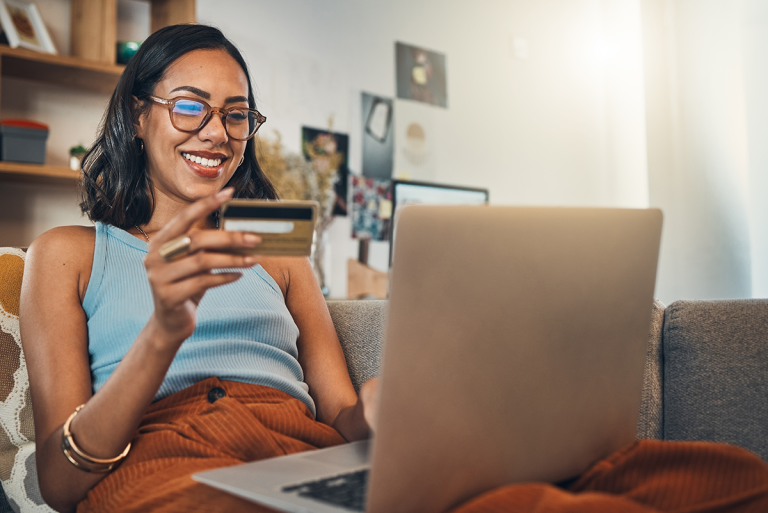 Woman in glasses holding credit card looking at computer