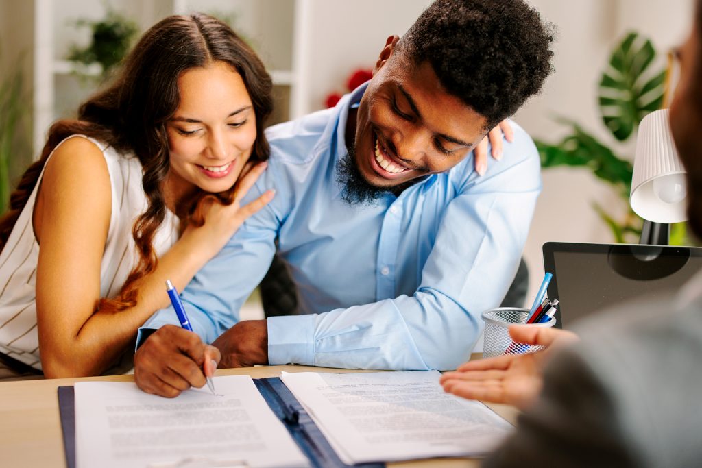 Young couple signing a contract with an agent in the office